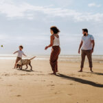 Séance photo à Oye-Plage, prise à la plage. Montrant une famille jouant sur le sable à lancer la balle à leur chien